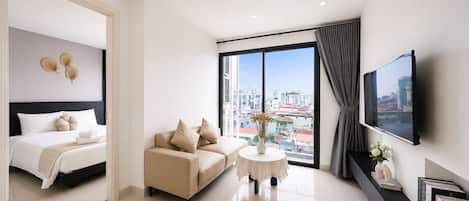 Una habitación de hotel moderna con cama, sofá, una mesita y televisor.