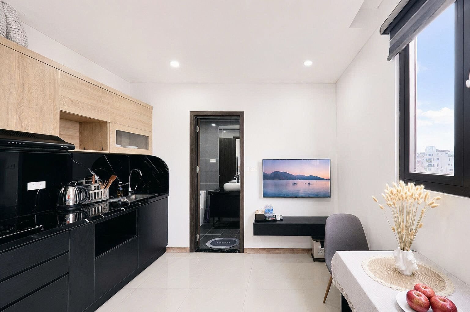 Una cocina moderna con electrodomésticos negros, un comedor con mesa y sillas, y un ventanal con vistas a la ciudad.