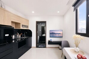 Una cucina moderna con elettrodomestici neri, un'area pranzo con tavolo e sedie, e un'ampia finestra con vista sulla città.