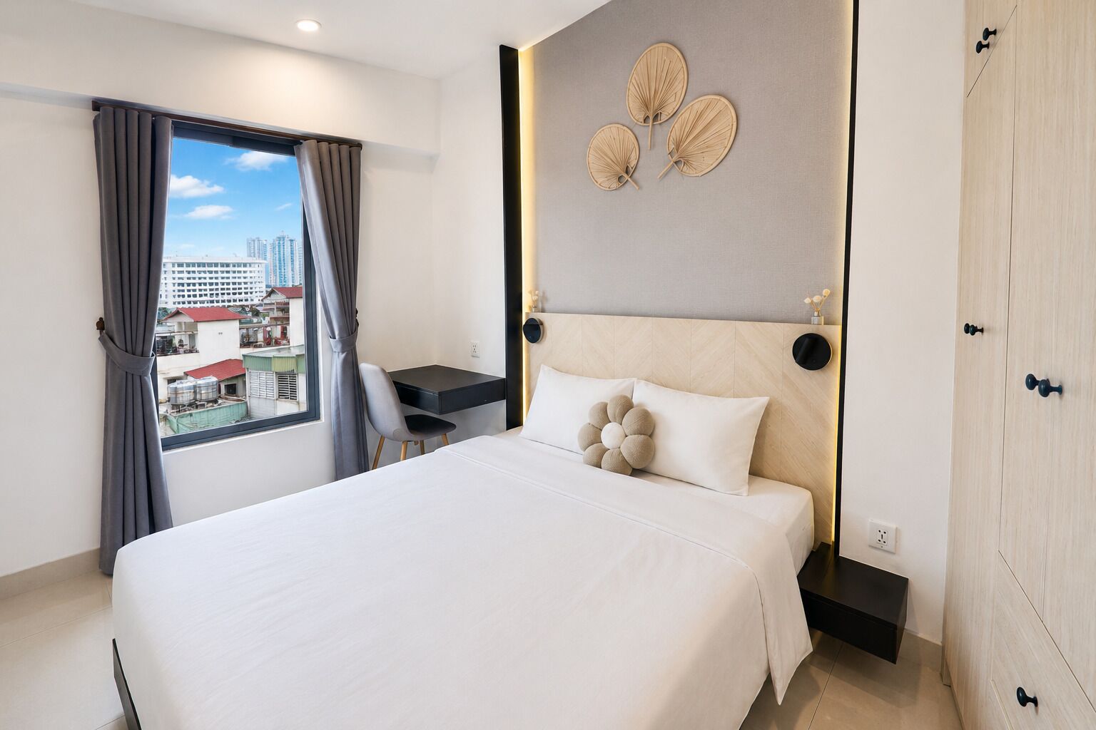 Una habitación de hotel con cama, escritorio, silla, armario y vistas a la ciudad.