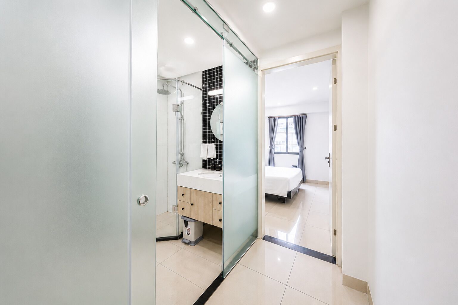 A modern bathroom with a glass shower enclosure, a white sink, and a mirror.
