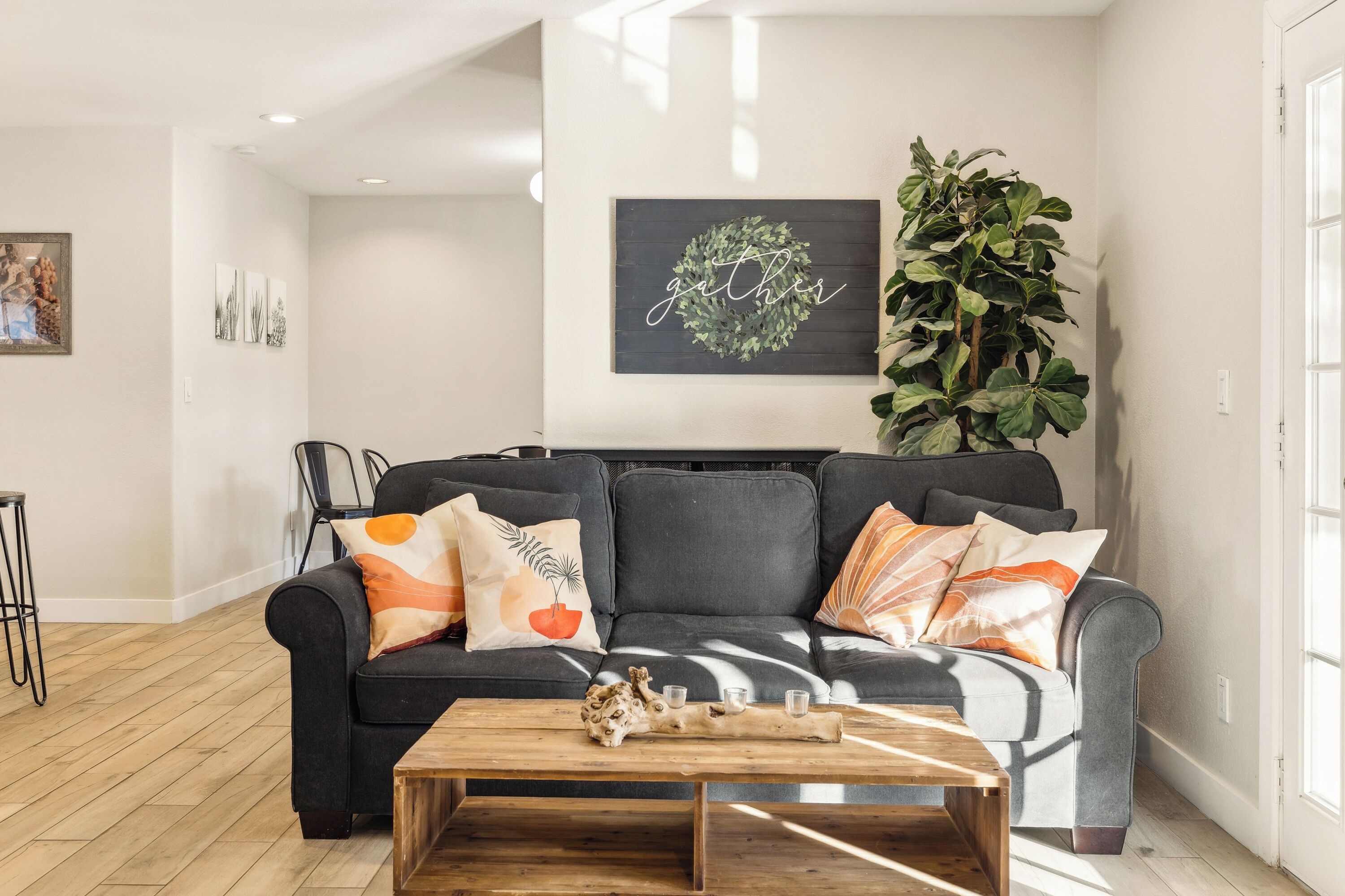 A modern living room with a grey sofa, wooden coffee table, and a large green plant.