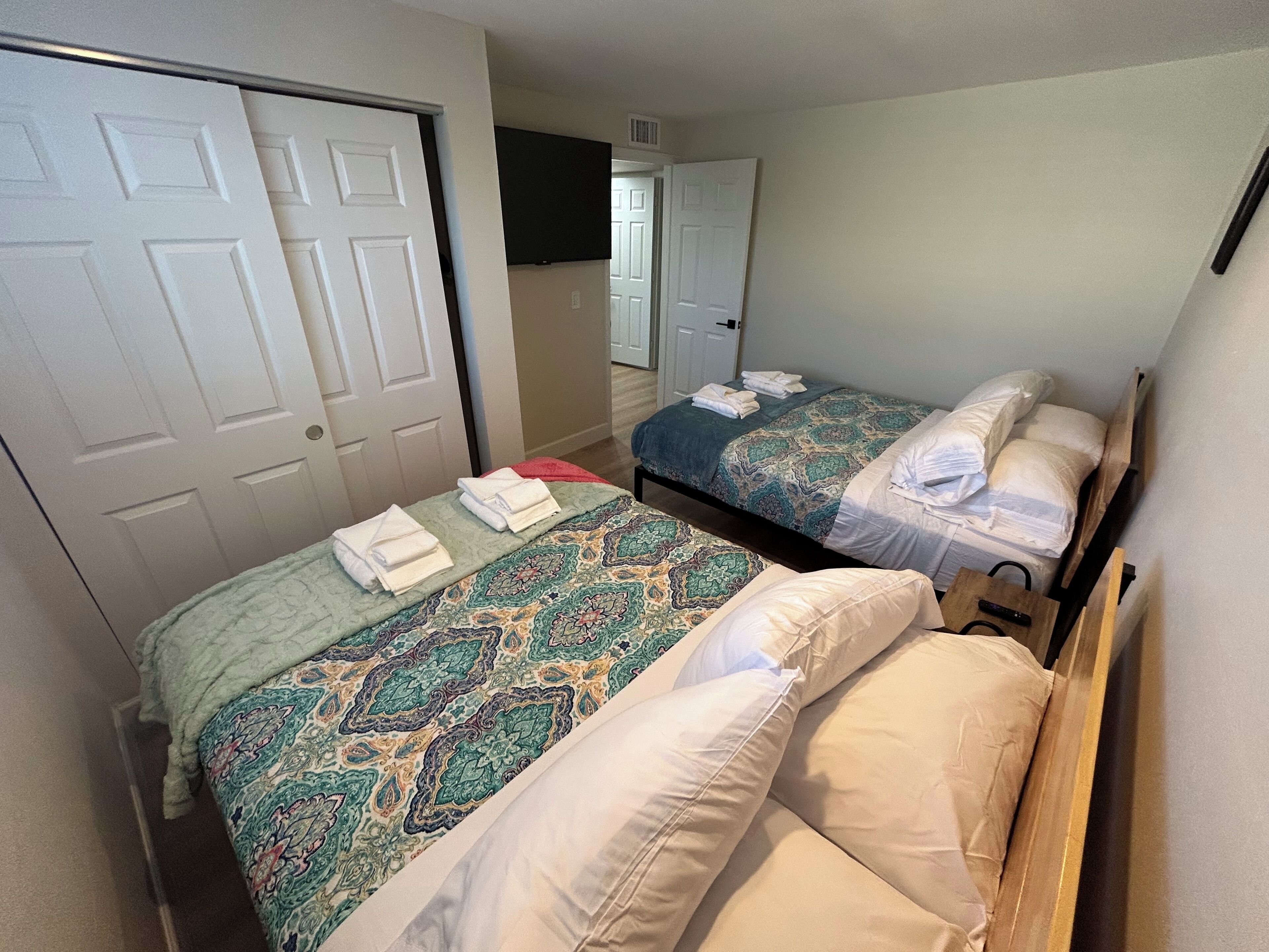 two Queen-size beds, a TV, and a large closet for ample storage space.