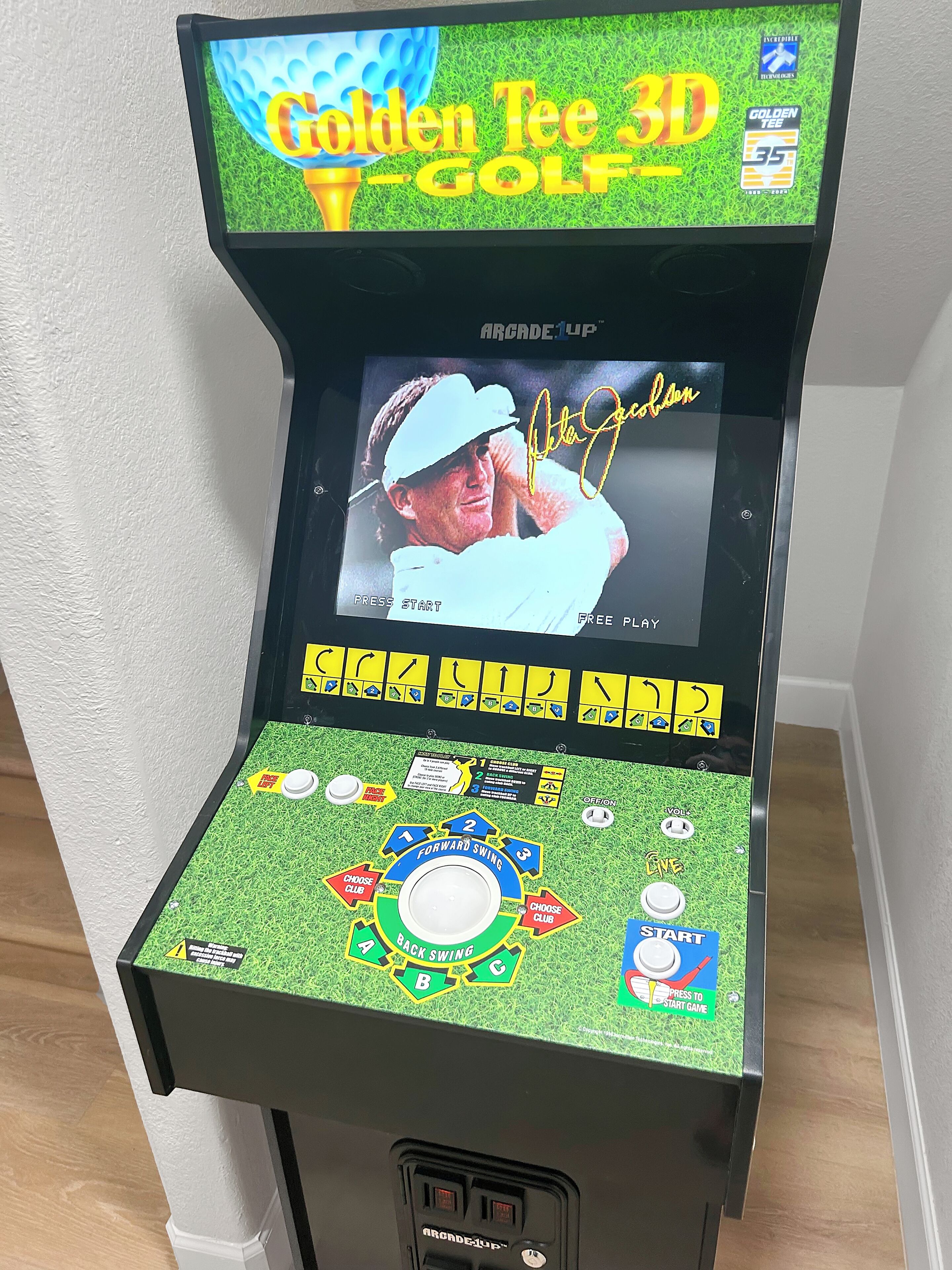A 3D golf arcade machine with a grass-textured playfield, a screen displaying a golfer, and various control buttons.