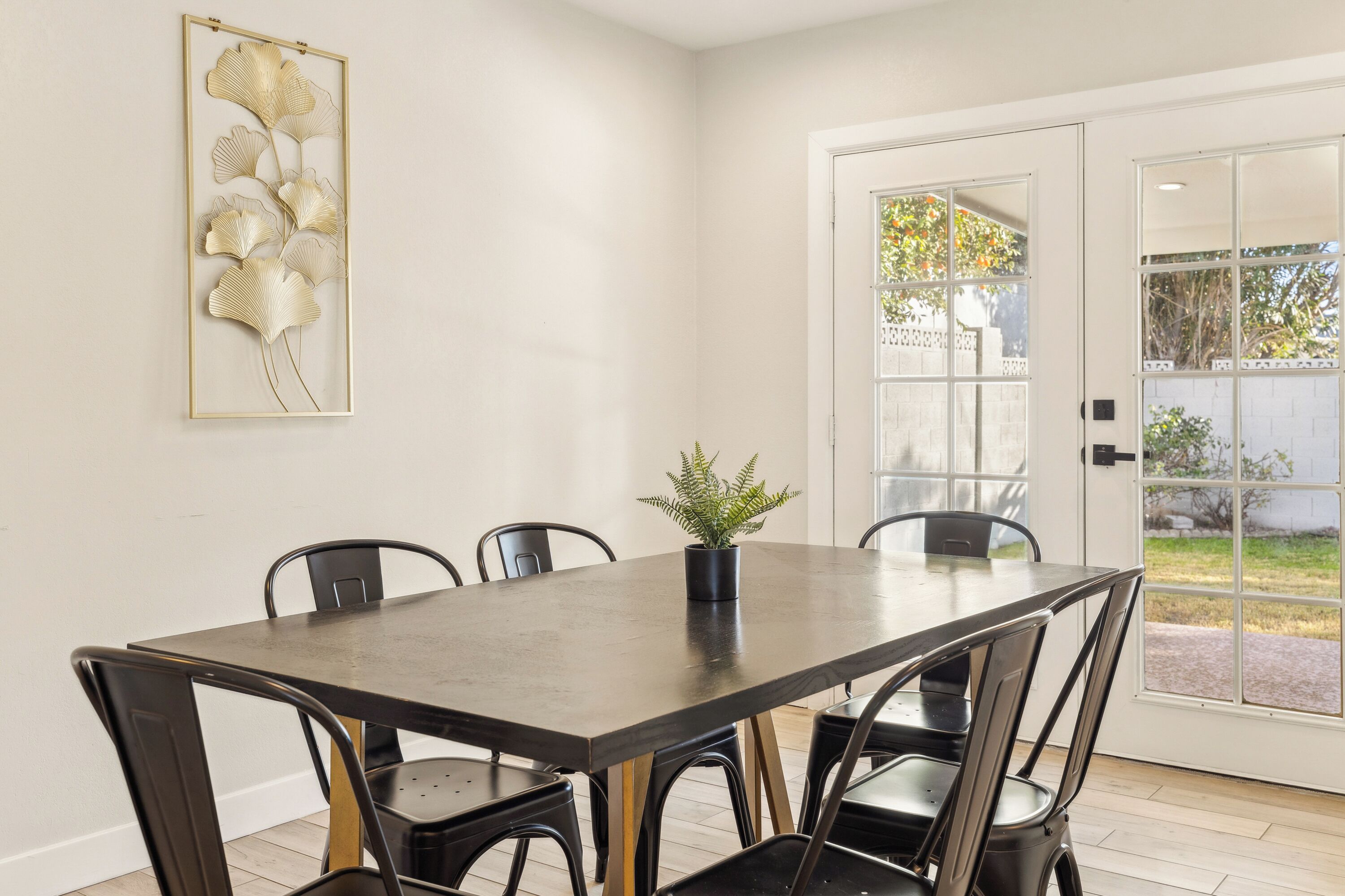 A dining area with a dark wooden table, black chairs, and a potted plant.