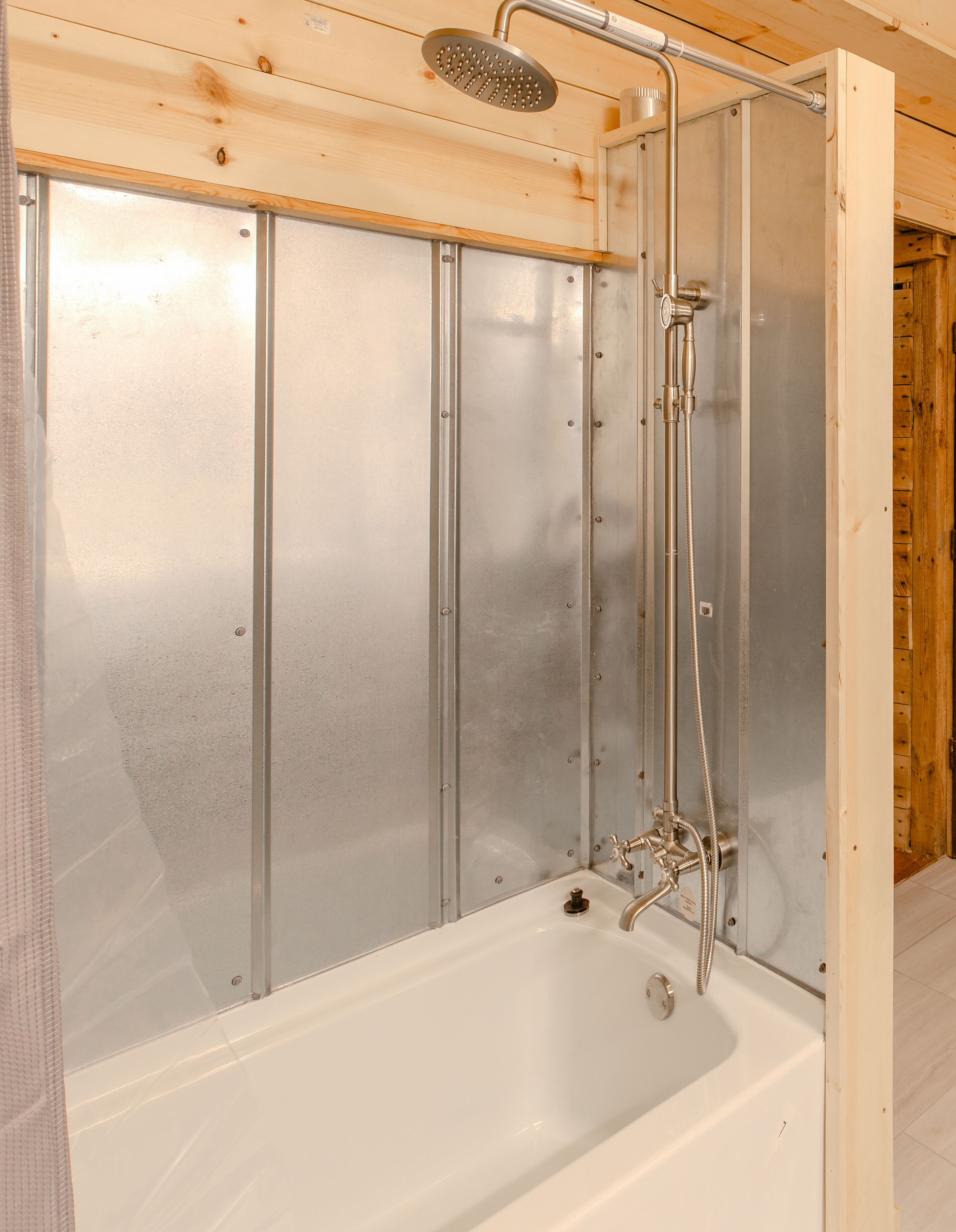 A shower enclosure with a glass door, a handheld showerhead, and a handheld shower hose.