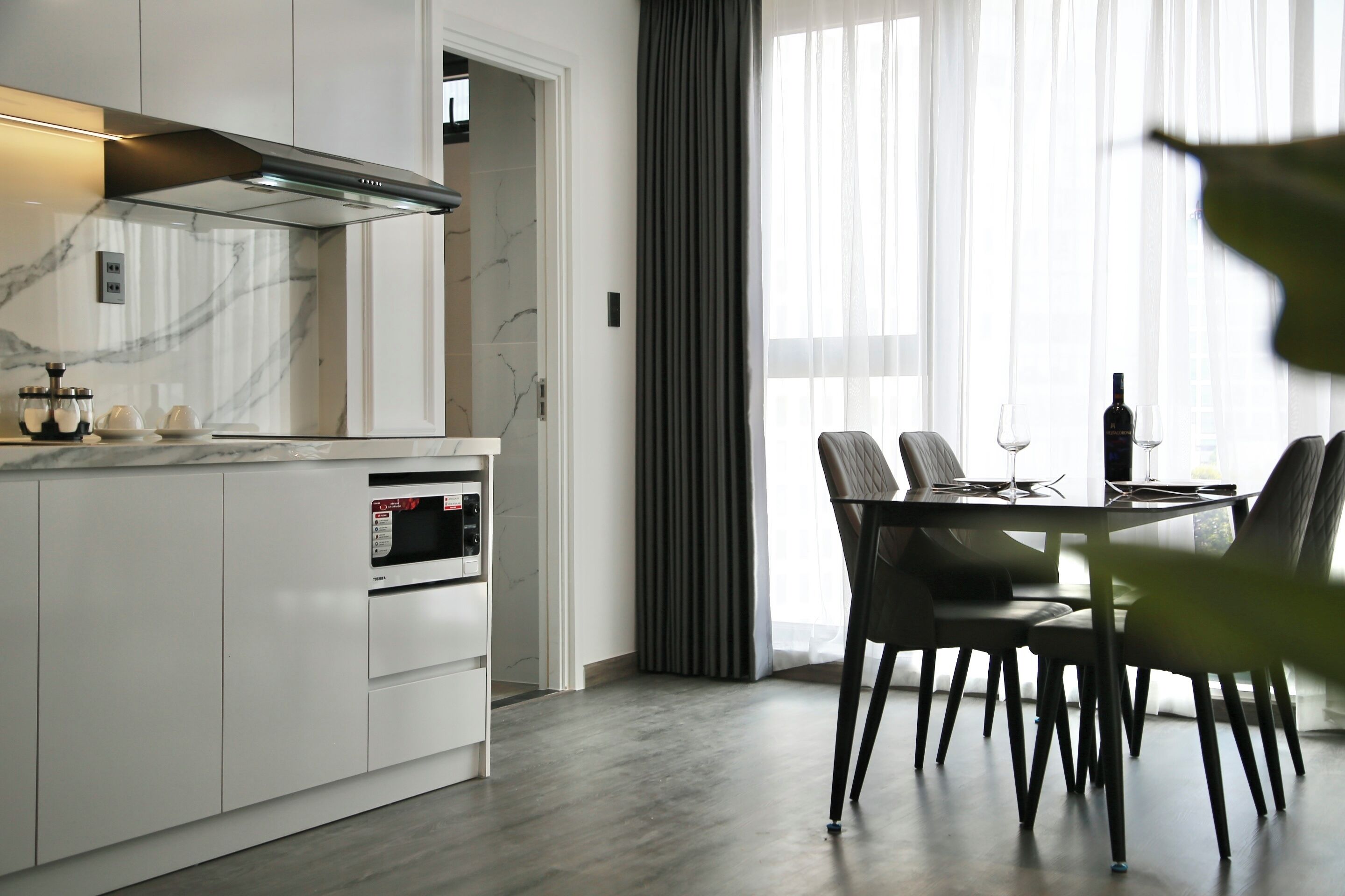 A modern kitchen with a built-in oven and a dining area with a table and chairs.