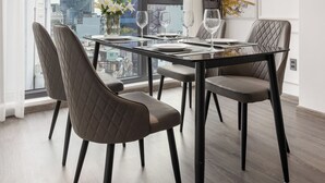 A modern dining area with a city view, featuring a glass table, leather chairs, and a contemporary art piece. - CityHouse - El Pino Realm at Metro Ben Thanh Market (Ho Chi Minh City)