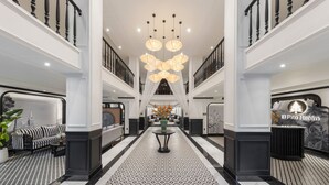 A spacious lobby with a high ceiling, a central chandelier, and a symmetrical design with a black and white patterned floor. - CityHouse - El Pino Realm at Metro Ben Thanh Market (Ho Chi Minh City)