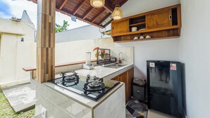 Une cuisine de taille réduite, équipée d’une cuisinière à gaz, d’un évier et d’un réfrigérateur noir.