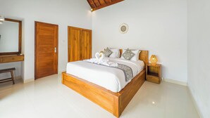 Une chambre à coucher avec un cadre de lit en bois, du linge de lit blanc, un miroir, un luminaire fixé au mur et une petite table de chevet avec une lampe.