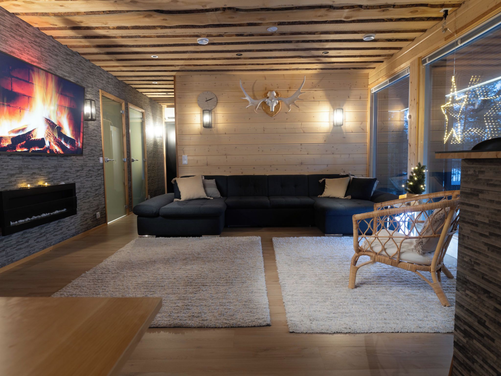 A modern living room with a sectional sofa, a fireplace, and a large wall-mounted TV.