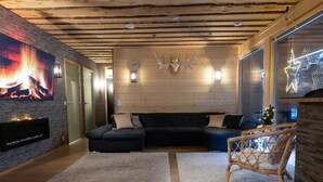 En hyggelig stue med pejs, en stor modulsofa og træloft.