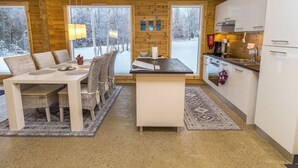 Una cocina moderna con una isla central, armarios blancos y ventanas amplias que ofrecen vistas a un paisaje nevado.