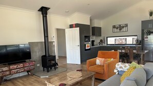 A modern living room with a fireplace, a television, a sofa, and a dining area.