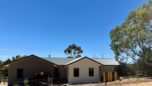 A two-story house with a metal roof, a garage, and a fenced yard.