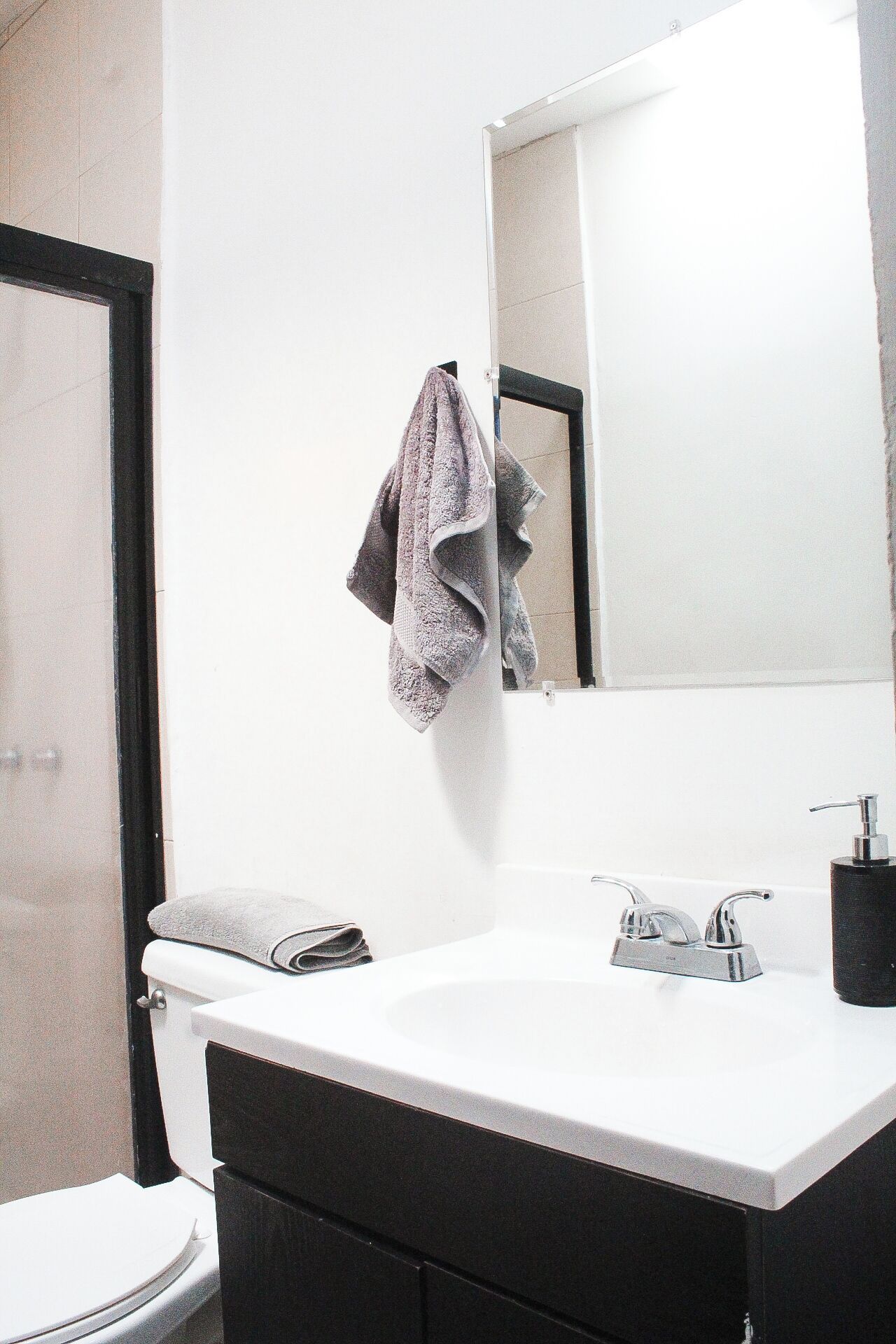 A bathroom with a white sink, a mirror, a towel, and a toilet.