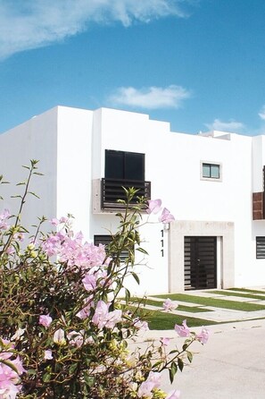 A modern two-story building with a flat roof, a small balcony, and a number '111' on the facade.