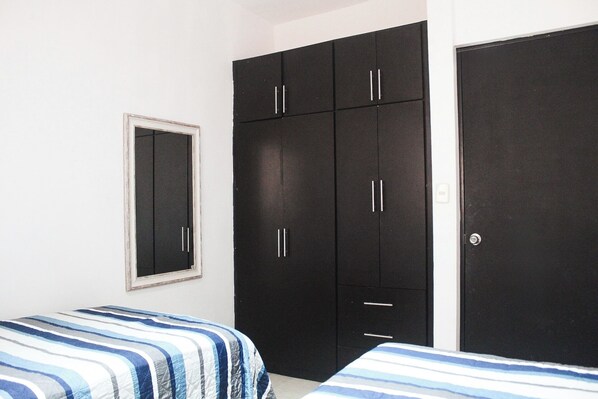 Un dormitorio con cama, armario y espejo.