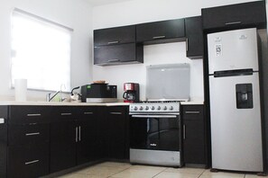 Una cocina equipada con estufa, microondas y refrigerador.