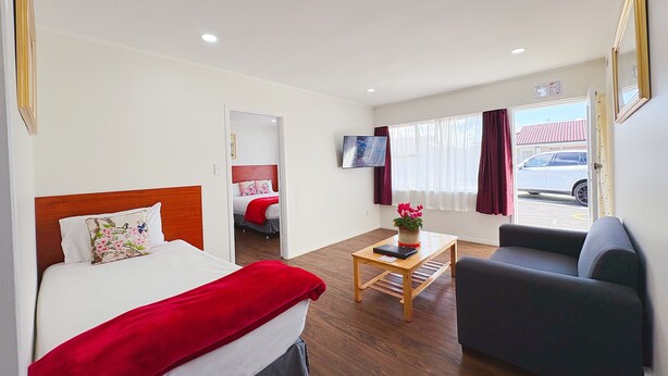 Una camera d'albergo con un letto, una scrivania, una sedia, una televisione e una finestra con tende.