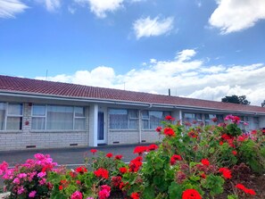 Guests can enjoy a peaceful stay in this charming motel with a brick facade, surrounded by vibrant flowering plants.