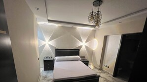 Un dormitorio moderno con una cama grande, una mesita de noche, una lámpara y un diseño geométrico en la pared.
