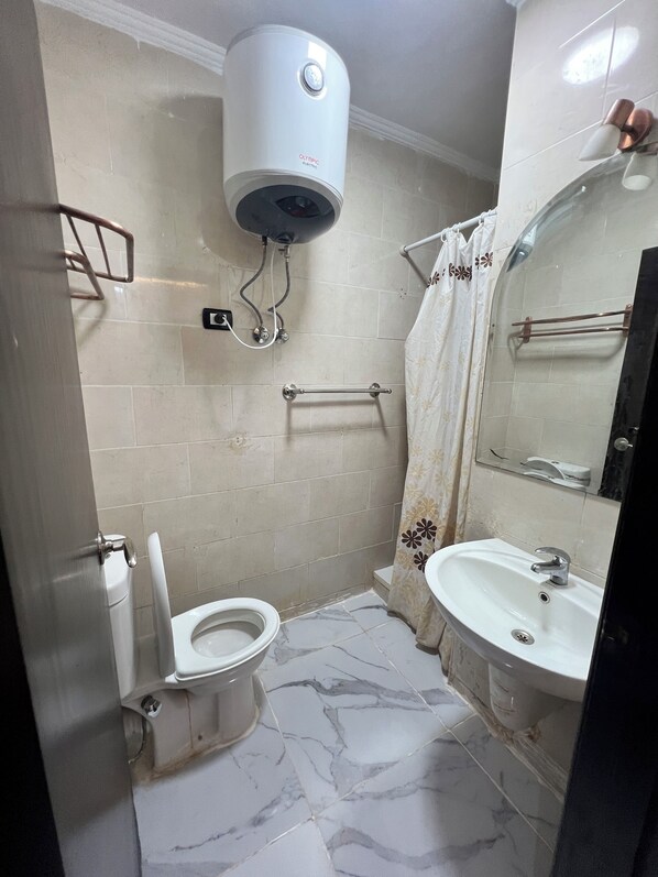 A bathroom with a toilet, sink, and a water heater.