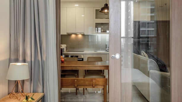 A modern kitchen with white cabinets, a dining table with chairs, and a pendant light.