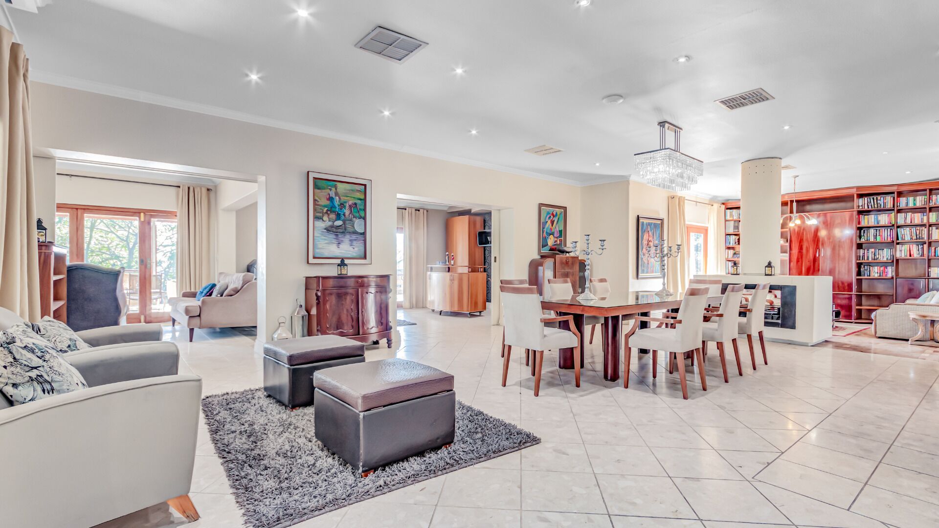 A spacious living room with a dining area, a library, and a kitchen.