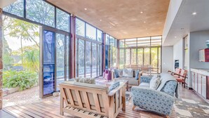A spacious indoor area with large windows, a wooden bench, and a patterned sofa. - House Sunbeam GuestHouse (Johannesburg)