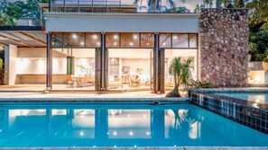 A modern house with a swimming pool, large windows, and a stone wall. - House Sunbeam GuestHouse (Johannesburg)