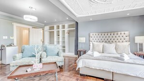 A modern bedroom with a large bed, a sofa, a desk, and a walk-in closet. - House Sunbeam GuestHouse (Johannesburg)