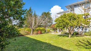 Ein gepflegter Garten mit Rasen, verschiedenen Sträuchern und Bäumen.