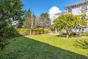 A well-maintained garden with a lawn, various shrubs, and trees. - Spacious House in Walking Distance to the Beach (Aptos)