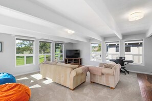 A spacious living room with large windows, a flat-screen TV, and a piano. - Spacious House in Walking Distance to the Beach (Aptos)