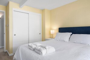 A hotel room with a bed, a nightstand, a lamp, and a door. - Spacious House in Walking Distance to the Beach (Aptos)
