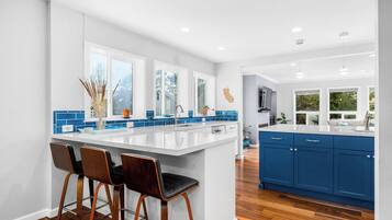 A modern kitchen with a large island, bar stools, and blue cabinets.