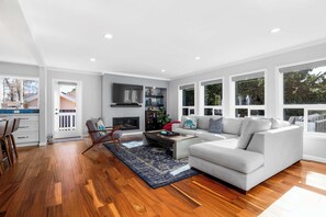 A modern living room with a grey sofa, wooden flooring, and a fireplace.