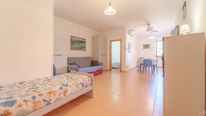 A compact room with a bed, a sofa, a dining table with chairs, and a refrigerator. - APPARTAMENTI GLI ORIZZONTI - ORIZZONTI BILO 4 (Campo nell'Elba)