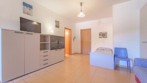 A spacious room with a large wardrobe, a bed with a floral bedspread, and a blue chair. - APPARTAMENTI GLI ORIZZONTI - ORIZZONTI BILO 4 (Campo nell'Elba)