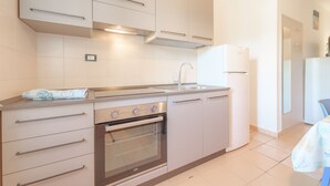 A modern kitchen with a built-in oven, stainless steel appliances, and a white refrigerator. - APPARTAMENTI GLI ORIZZONTI - ORIZZONTI BILO 4 (Campo nell'Elba)