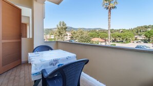 A balcony with a table and chairs, overlooking a residential area with houses and a palm tree.