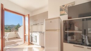 Una cocina con armarios blancos, un refrigerador y un comedor con vitrina de vidrio.