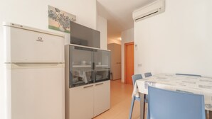 Cocina compacta con refrigerador, un armario de vidrio y un comedor con mesa y sillas.