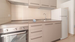 Een moderne keuken met roestvrijstalen apparatuur, beige keukenkastjes en een inbouwoven.