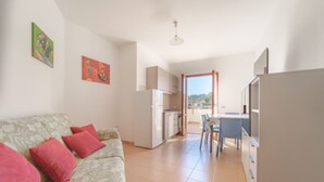 A modern apartment with a living area, kitchenette, and a balcony with a view.