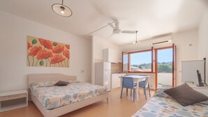 A bedroom with two beds, a desk, and a chair. - APPARTAMENTI GLI ORIZZONTI - ORIZZONTI MONO 22 (Marina di Campo)