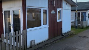Een laag, enkelvoudig gebouw met een witte en bruine gevel, een schotelantenne en een klein raam.