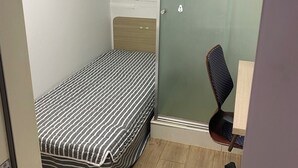 Une petite pièce, de taille modeste, comprenant un lit, un bureau et une chaise.